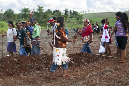 Suedamerika, Brasilien, Mato Grosso do Sul, Caarapo, 23.02.2013: Gruppe von Indigenen der Ethnie Guarani-Kaiowa mit Gesichtsbemalung und Federschmuck tanzt um Grab auf abgeerntetem Sojafeld einer besetzten Farm. Als Reaktion auf den von einem Sojafar / © Werner Rudhart, Werner Rudhart Suedamerika, Brasilien, Mato Grosso do Sul, Caarapo, 23.02.2013: Gruppe von Indigenen der Ethnie Guarani-Kaiowa mit Gesichtsbemalung und Federschmuck tanzt um Grab auf abgeerntetem Sojafeld einer besetzten Farm. Als Reaktion auf den von einem Sojafar